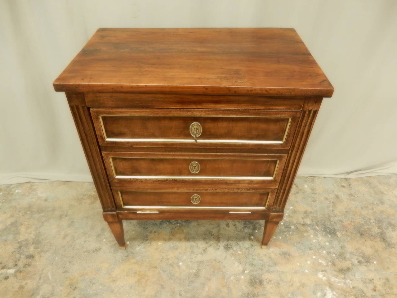 Carefully restored Louis XVI style small walnut faux 3-drawer fall front commode with brass trim.  Opens with one shelf inside.