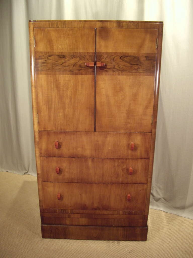 1930's converted Art Deco walnut bar cabinet with bakelite pulls and contrasting grain inlay. 2 doors and 3 draws. Mirrored back and glass shelf.