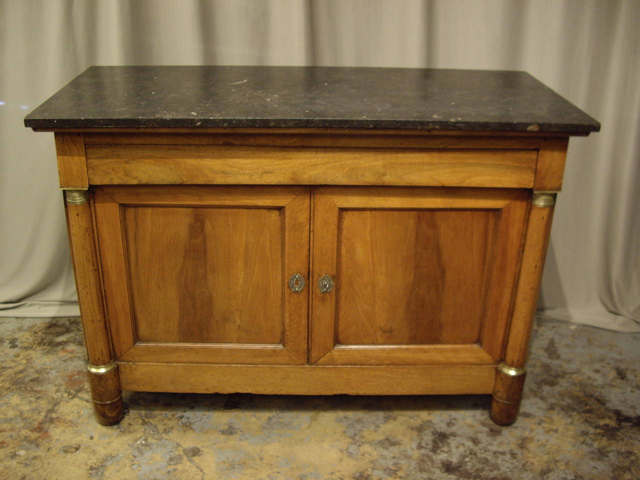 Honey colored patina French Empire walnut buffet with black marble top.