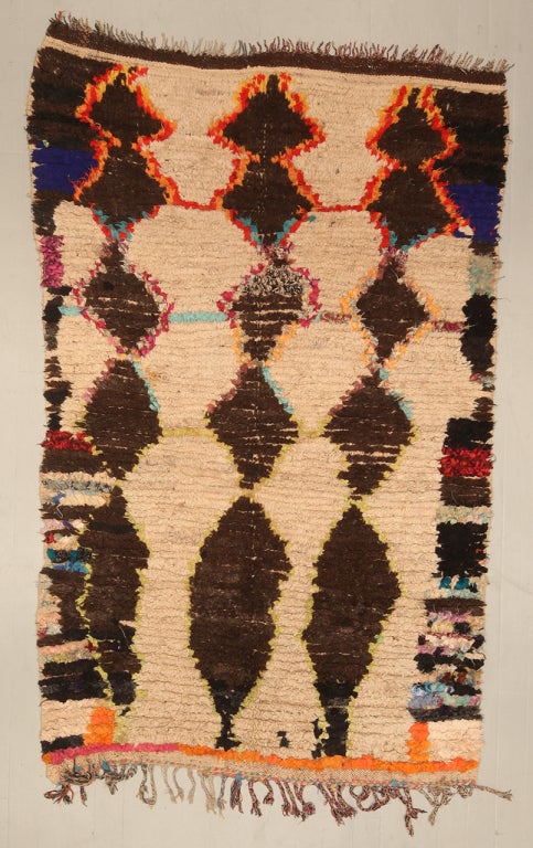 A vintage Moroccan Rug  with a typical diamond motif rendered in a more modern color palette, aligned in rows from top to bottom.
