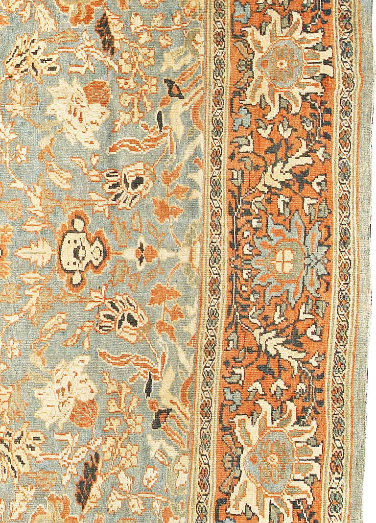A late 19th century antique Sultanabad rug, the abrashed blue field with an angular vine and geometric flowerhead trellis overall within a rust red enlarged palmette border.