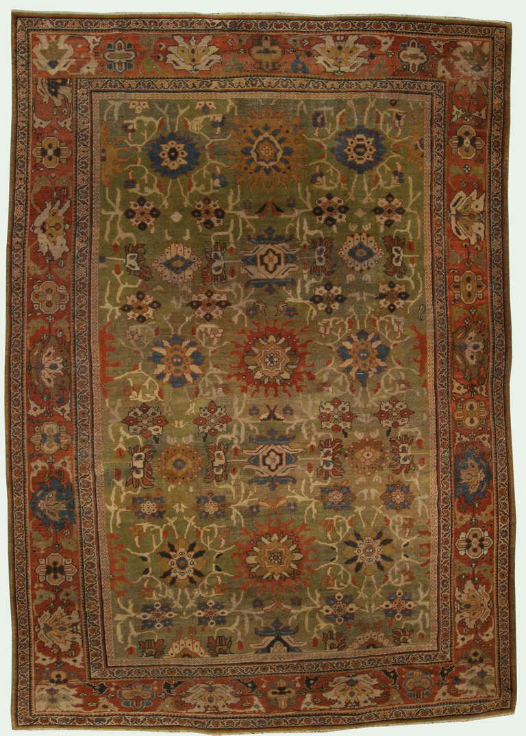 An early 20th century Persian Sultanabad antique rug, the moss green field with an enlarged palmette, flowerhead, and angular vine trellis overall within a brick red palmette border.