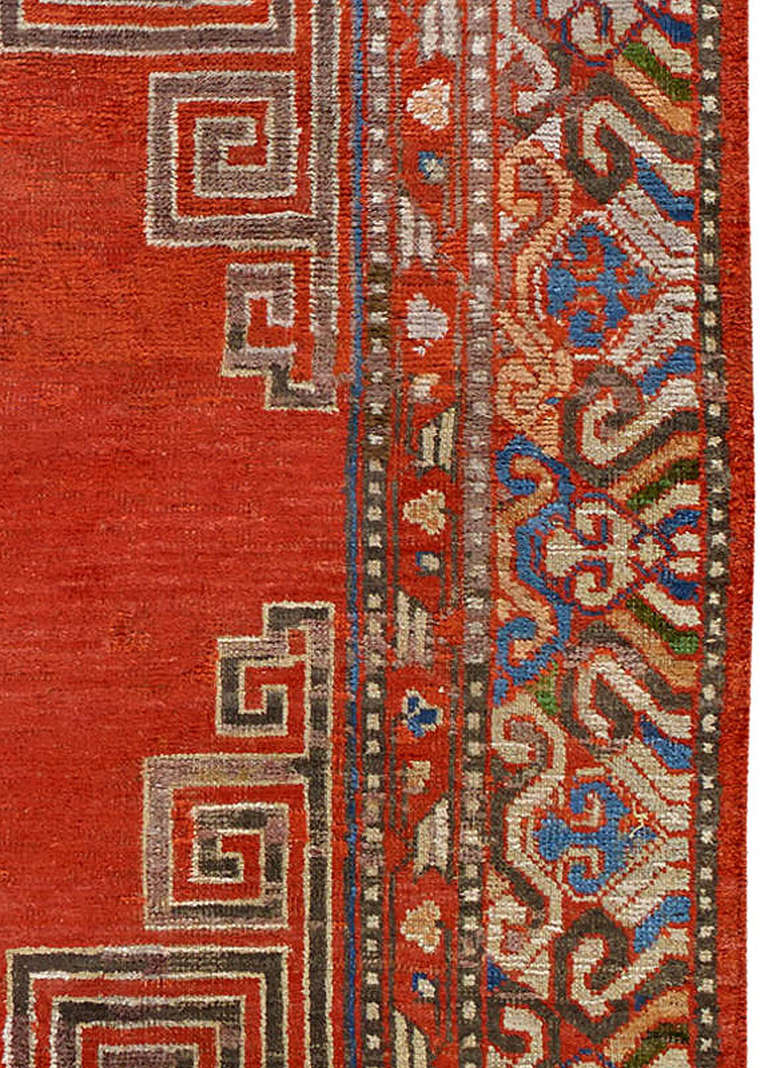 An early 20th century Samarkand (Khotan) rug, with stylized Greek keys dividing the ample vermilion background in three equal parts directing the eye on three central circular blue medallions. The busy decorative border creates a pleasant contrast