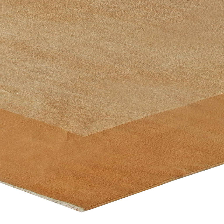 A mid-century modern Indian Dhurrie rug, the open beige field with a broad open camel border.