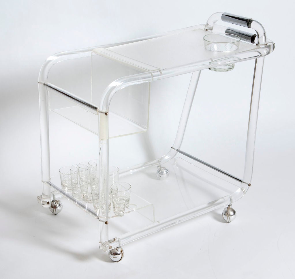 Sleek lucite and chrome bar cart perfect for a party, or poolside.  Plenty of space on the shelves to store bottles and bar accessories.  Glassware included; clear with an etched chevron pattern.