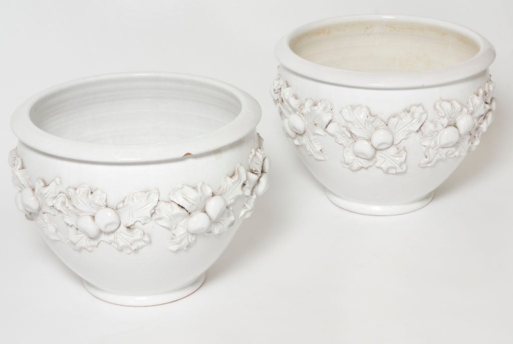Pair of white glazed pots for indoor or outdoor use.  The sides have a great fruit or botanical raised design.  Priced as a pair.