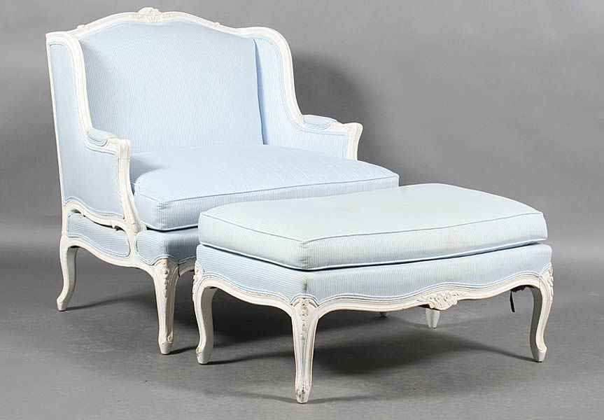 A Louis XV style Bergere chair with matching ottoman.  The frame is carved wood and painted white.  Priced as a set.