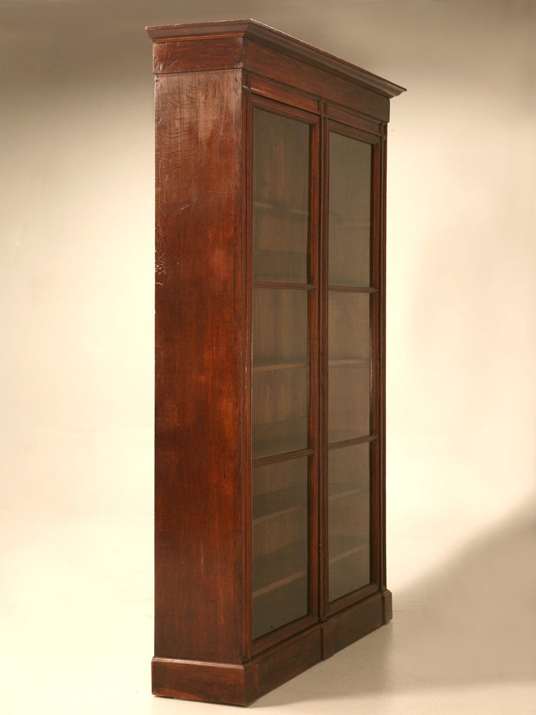 One-of a-kind original antique French solid oak bookcase or cabinet from the early 1800s. This cabinet has perfect proportions, an elegant stepped crown, adjustable shelves and original wavy glasses. The original finish was recently treated with