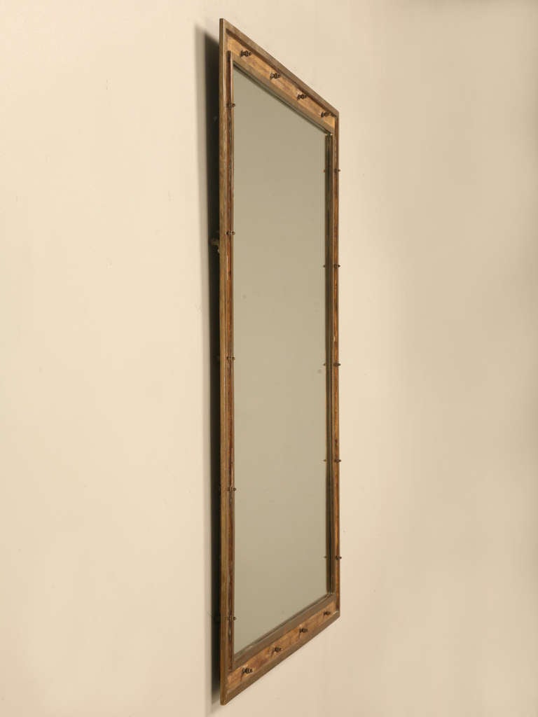 A work of art, this vintage French mirror is truly unique with its raised brass edges on either side of the gold leafed recess, groove or channel. Perfectly spaced, the rivet detail adds extra industrial appeal to this already alluring mirror.
