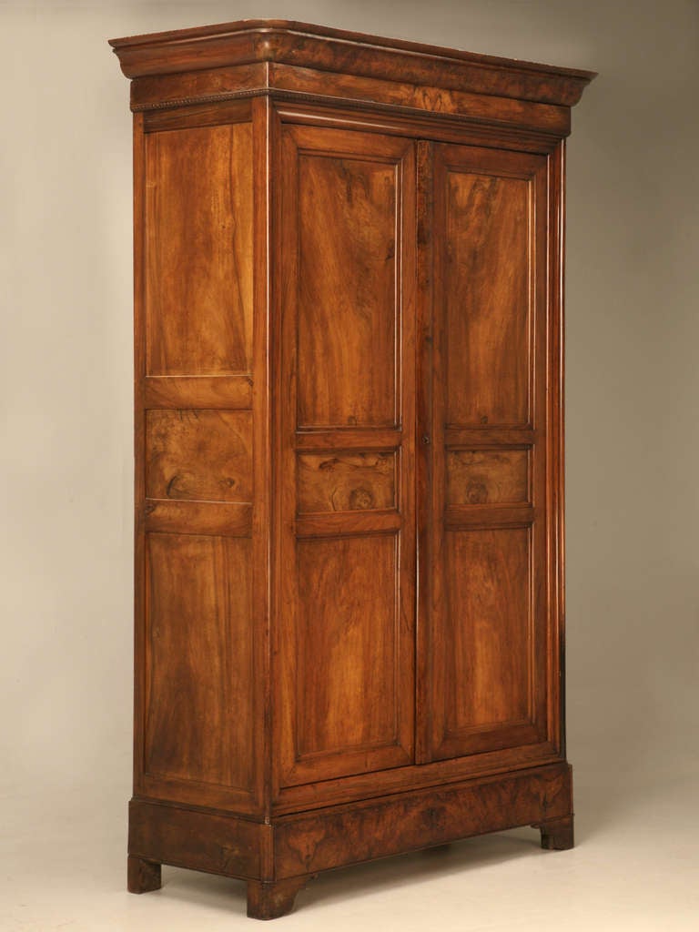 Authentic original antique French Louis Philippe armoire hailing from the 1830s. Expertly constructed of figured walnut, the wood glows showcasing its distinctive grain. Storage is abundant with lots of shelves, there is also a full width drawer