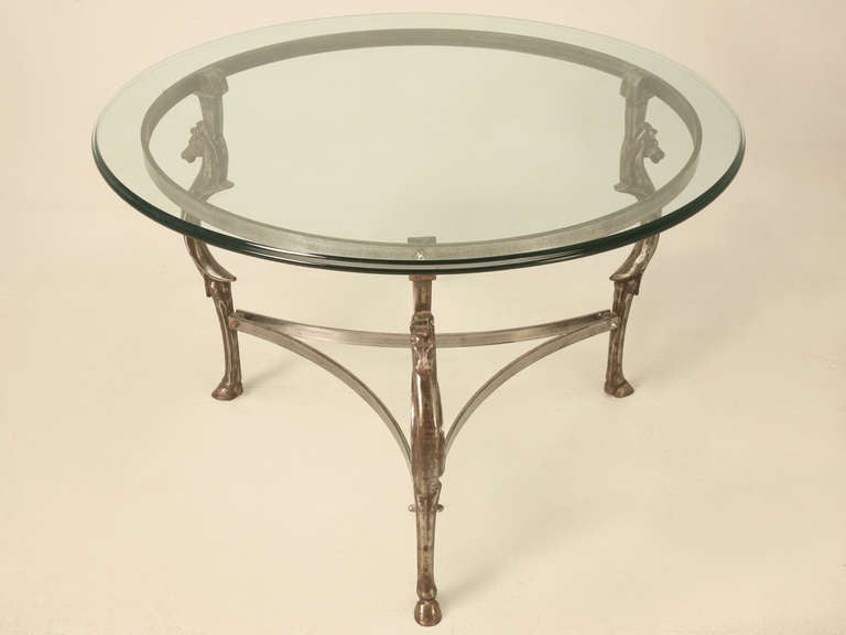 Three intricately cast iron horse legs, connected by exceptionally thick cold roll steel banding, completed in a natural burnished finish. Glass top is nicely detail with an ogee edge. Beautifully constructed in France during the late 1940’s and can