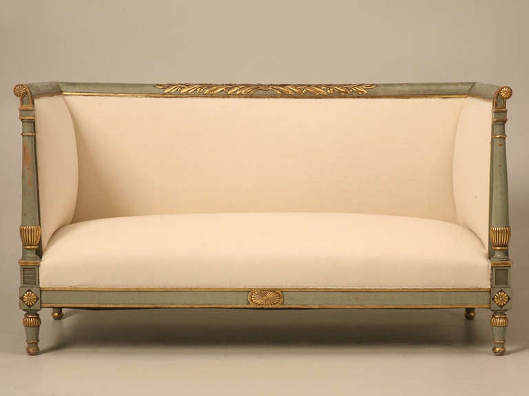 Outstanding antique Directoire style settee with original paint and gilding. The rectilinear back has gilded foliage relief and the high sides terminate in scrolled ends which are highlighted with gilded rosettes. This detail is repeated in the