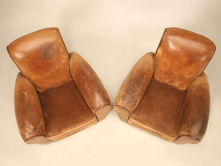 Great pair of 1940's club chairs. The leather exterior is all original. The foam rubber seat cushions were recovered in velvet that match well with the color of the chair at some earlier point in time. We tightened the springs in the base as well as