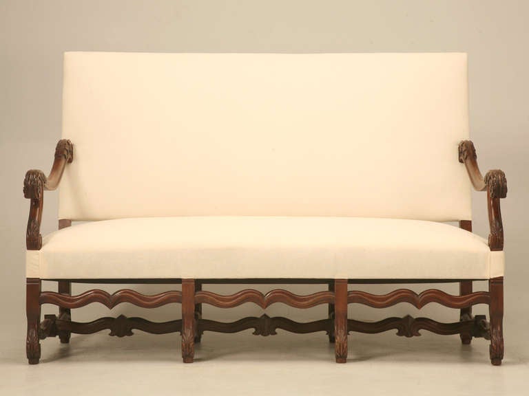 French three-seat sofa in the style of Louis XIV, circa 1890. Solid walnut frame, with new hand tied spring seat with proper horse hair padding. The newly tightened arms have a graceful floral motif. The legs and stretcher are classic os de mouton.