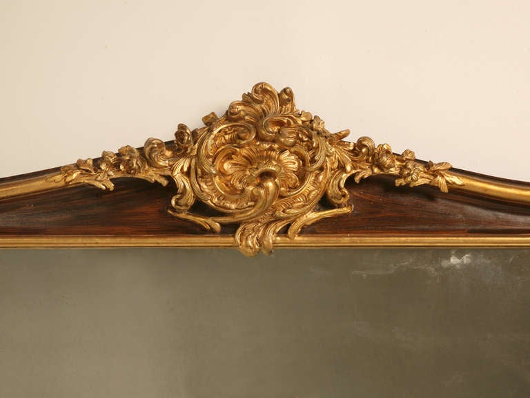 Framed in what we believe to be gilded 19th century window valances. The carved and detailed Rococo header on top on each mirror was most likely converted from a window treatment, which was commonly done, with 24K gold gilded decorations. Rich faux