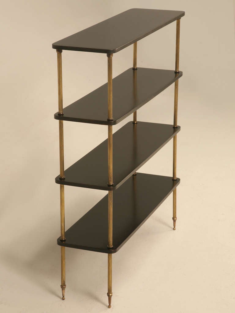 1970's etagere with black stained mahogany shelves. Spacers are brass plated fluted columns that gives this piece a truly classical look. Small in size but big storage capability. Finish on shelves is new, original finish on the brass supports.