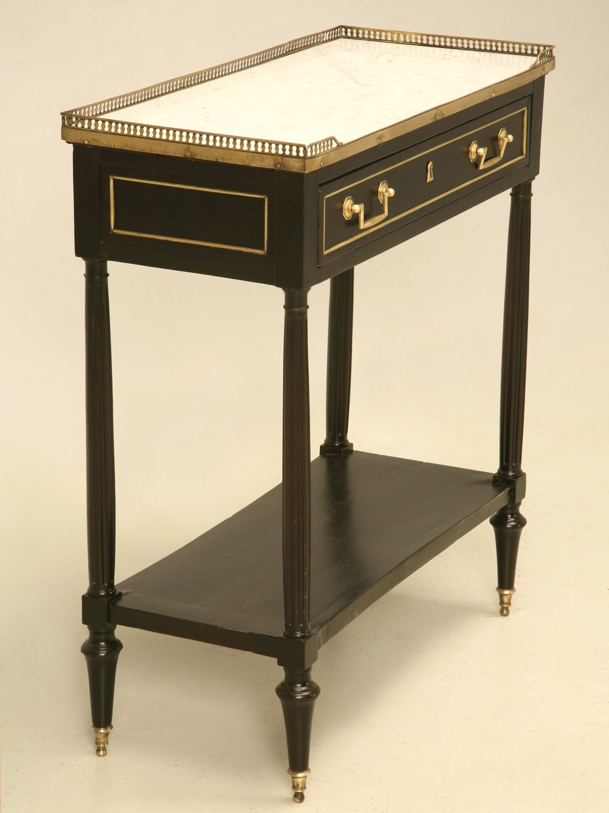 Antique French console table made from solid mahogany with a beautiful deep ebonized finish, original white marble top and a brass gallery, circa late 1800s. Please note old repairs to the gallery. Conversely the black finish is exquisite and