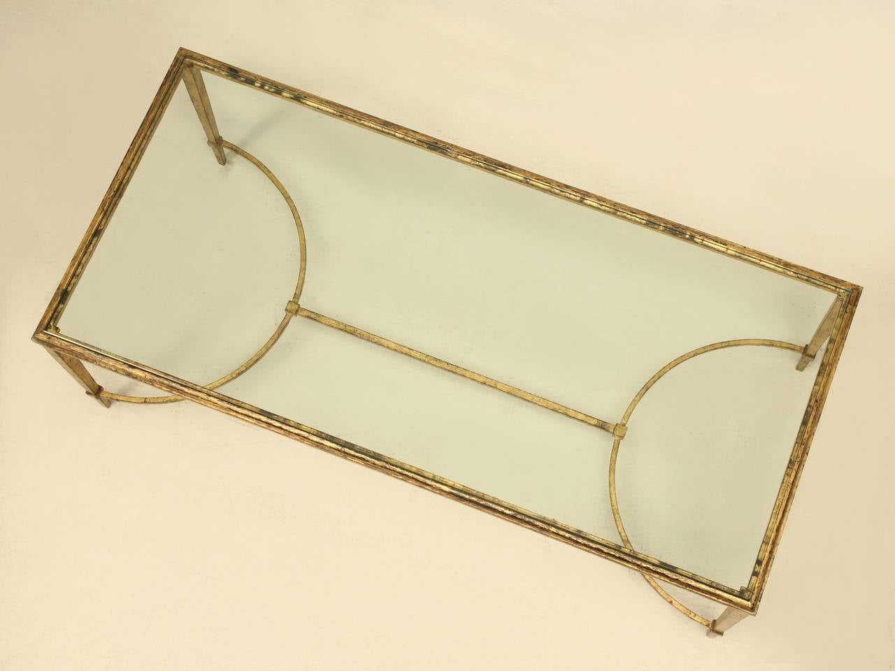 French Mid-Century Modern coffee table in the manner of Maison Ramsay and probably made in the late 1940s. Doré gilt metal with tapered legs and a thin stretcher connecting the legs with a beveled glass top. Simply elegant in its execution and