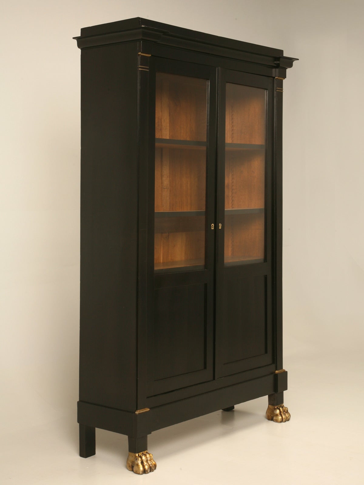 Beautifully proportioned ebonized mahogany bookcase, or bibliotheque, made in France during the mid-1800s. The gilded paw feet tie in quite nicely with the petite hints of gold on the raised moldings. Our Old Plank in house workshop completely