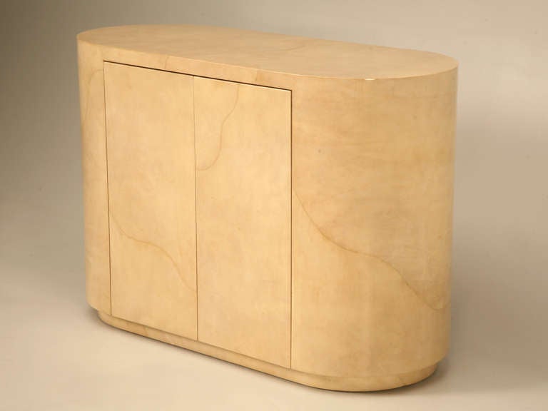 Extremely well executed, this fabulous parchment covered racetrack shaped cabinet is to die for. Three hidden interior drawers give this fine superior quality cabinet those clean lines of minimalistic design, most of us are drawn to. The parchment