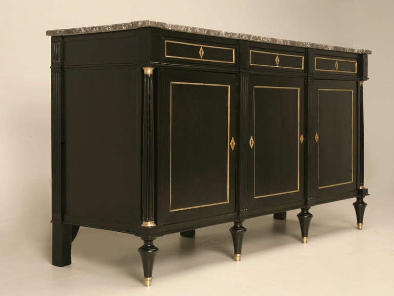 Louis XVI ebonized mahogany buffet with brass trim and a gray marble top. Restored both cosmetically and structurally and ready for the next 100 years of service. Beautifully proportioned with fluted columns, and diamond shaped escutcheons typical