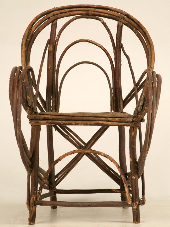 Handmade utilizing solid willow wood, ingeniously bent by hand and transformed into usable art. This spectacular chair retains it's original herringbone patterned seat and is in very good condition, especially for it's age. Perfect in a sunroom,
