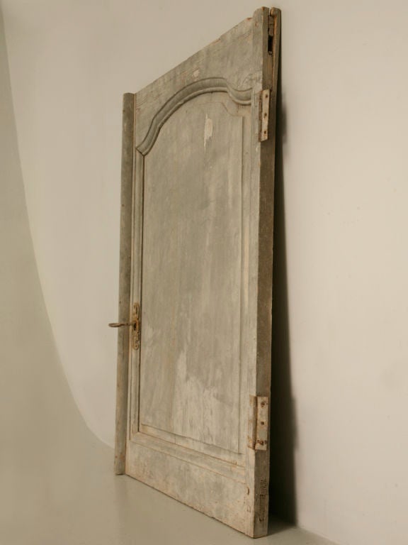 Original hand-carved 18th century French original paint panel just removed from a French chateau. A warm complimentary bluish putty gray finish highlights this fine architectural fragment utilized as a door.