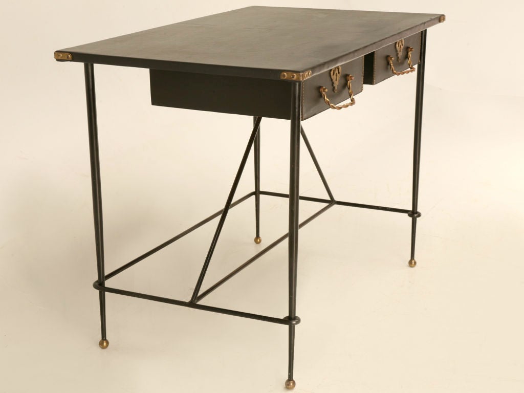 Clean uncluttered lines mixed with modern design and classic elements make this Jacques Adnet 2 drawer table really stand out. Brass corners, twisted pulls, and neat escutcheons all work well with the stitched leather drawer fronts of this dynamite