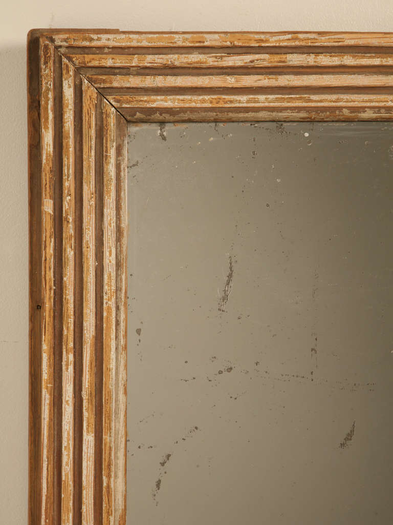 Circa 1860 French mirror with an unusual fluted frame. Upon close inspection, the mirror frame appears to always have been painted, although most of the finish has been worn off. The glass, or mirror itself is original to the frame, and the back of