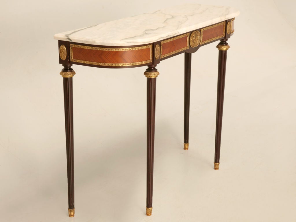 Breathtaking vintage French Louis XVI style console table with gilt metal trim, tapered fluted legs, and a marble top, to boot. Perfect in any room of the home, this fine table would be awesome utilized in a entry foyer, behind the sofa in a living