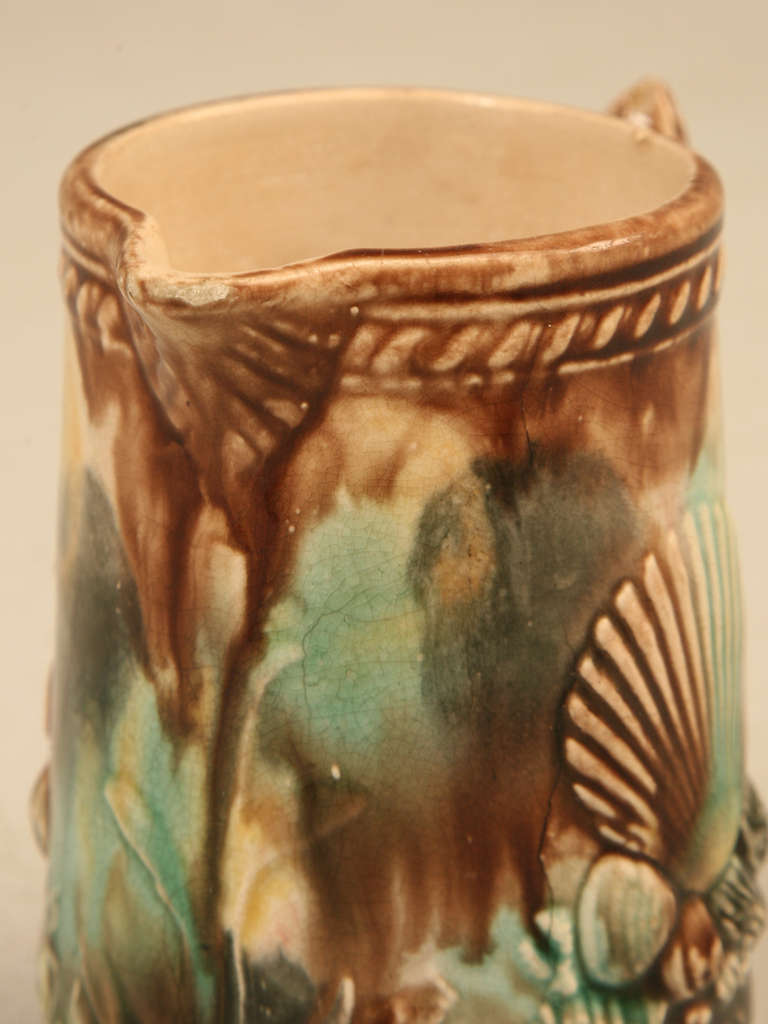 Circa 1880-1900 antique English majolica, maritime themed petite pitcher. Decorated with various types of seashells, rocks, anchor and seaweed. The handle is a fish and the entire exterior is glazed in a beautiful ocean color palette. Two minor