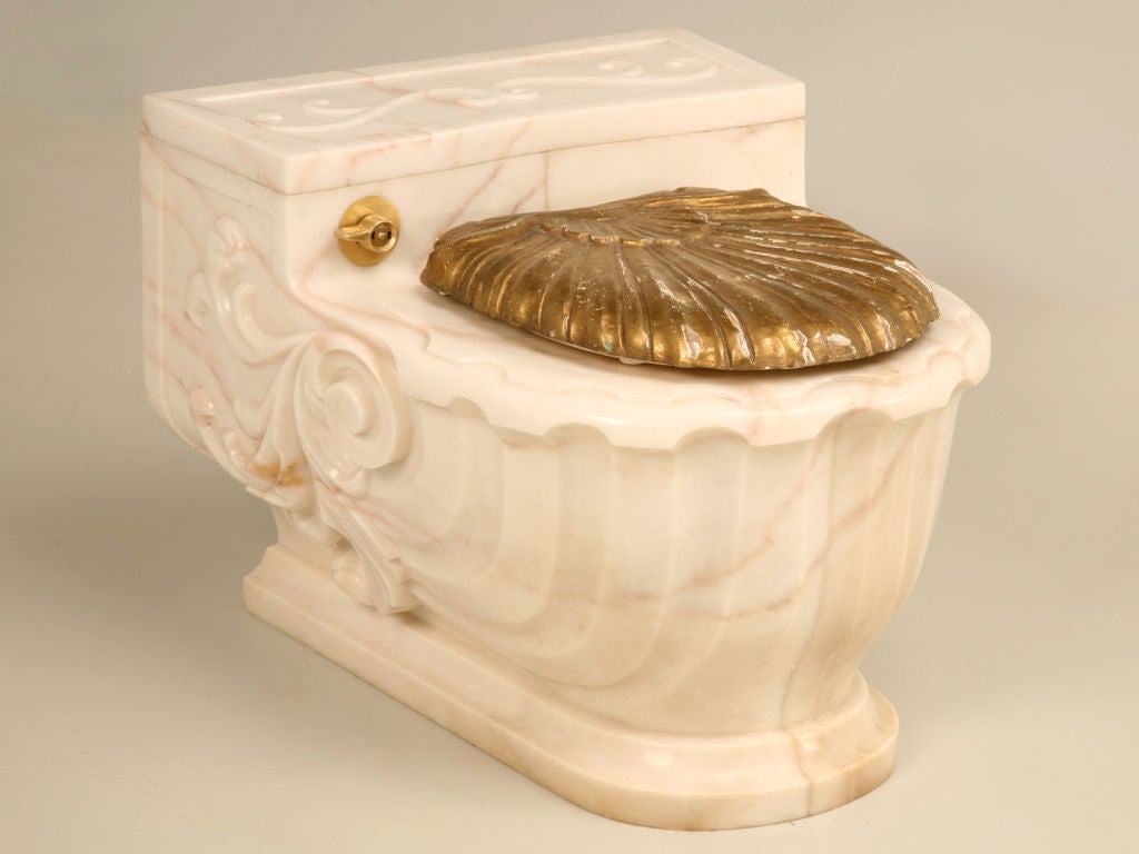 A magnificent work of art--this fine Sherle Wagner commode cover is still being sold today. Ingeniously designed to slide over a wall mounted commode, this scroll and flourish casing is the ultimate in luxury. Designed in a Aurora Marble Rose