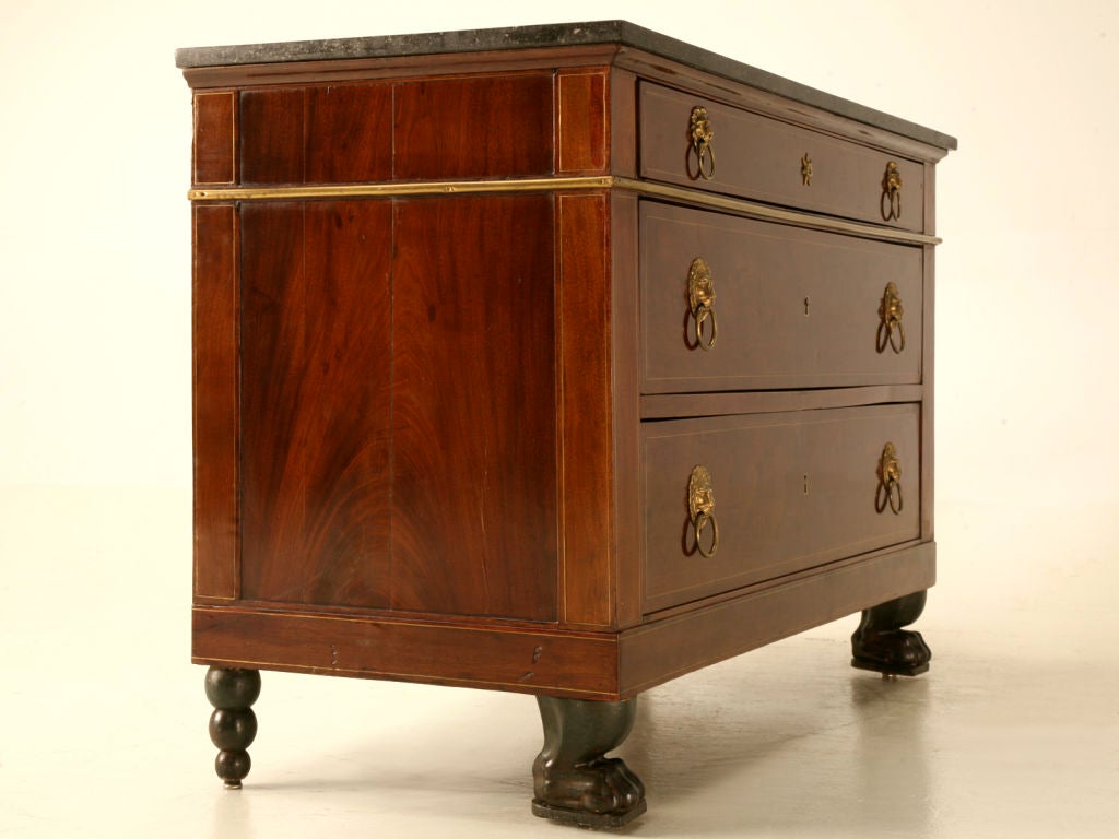 Exquisite antique French Restauration period 3 drawer commode with lion's head pulls, a marble top, and black paw feet. The superb craftsmanship shines in this delightful commode, from it's rich exotic appearing case to its expertly inlaid and