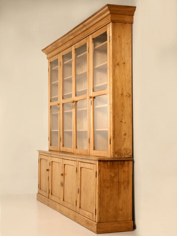 Spectacular original antique English pine 4 over 4 bookcase or china cabinet. This cabinet is extraordinary with its upper glazed doors, lower paneled doors, while being rather shallow as well. With its large size, it is sure to showcase many fine