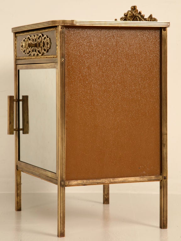 French 1940's brass, mirror and glass cupboard with a totally useful 1 drawer over 1 door configuration. Unique and unusual high quality construction of primarily brass and glass which was cutting edge in the '40's. The wavy glass mirror on the