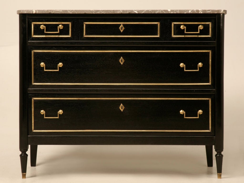 Phenomenal antique French Louis XVI ebonized commode with original polished brasses and contrasting marble top. This fine commode has 3 full width drawers providing ample storage, showing that it isn't just another pretty case. Though petite in