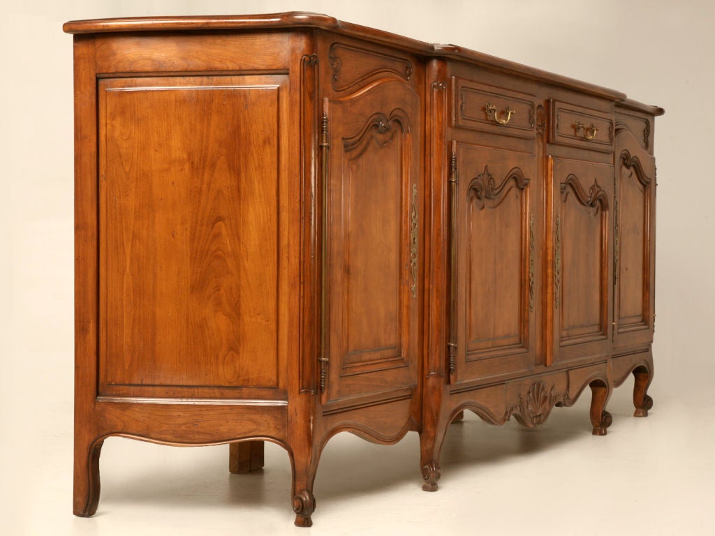 Striking as well as useful, this fantastic vintage French Louis XV style buffet is well constructed of highly desirable cherry-wood. With its useful 2 drawer over 4 door configuration paired with details such as serpentine ends, full length hinges,