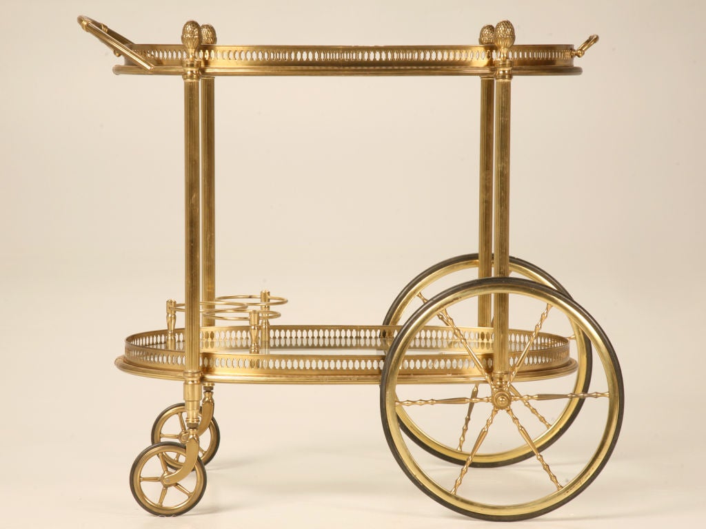 Dynamite, this wonderful vintage French oval brass tea or bar cart has a removable gallery edged tray top and bottle holders below. Once all the rage, tea carts were a highly sought after item due to their versatility and usefulness. Much like