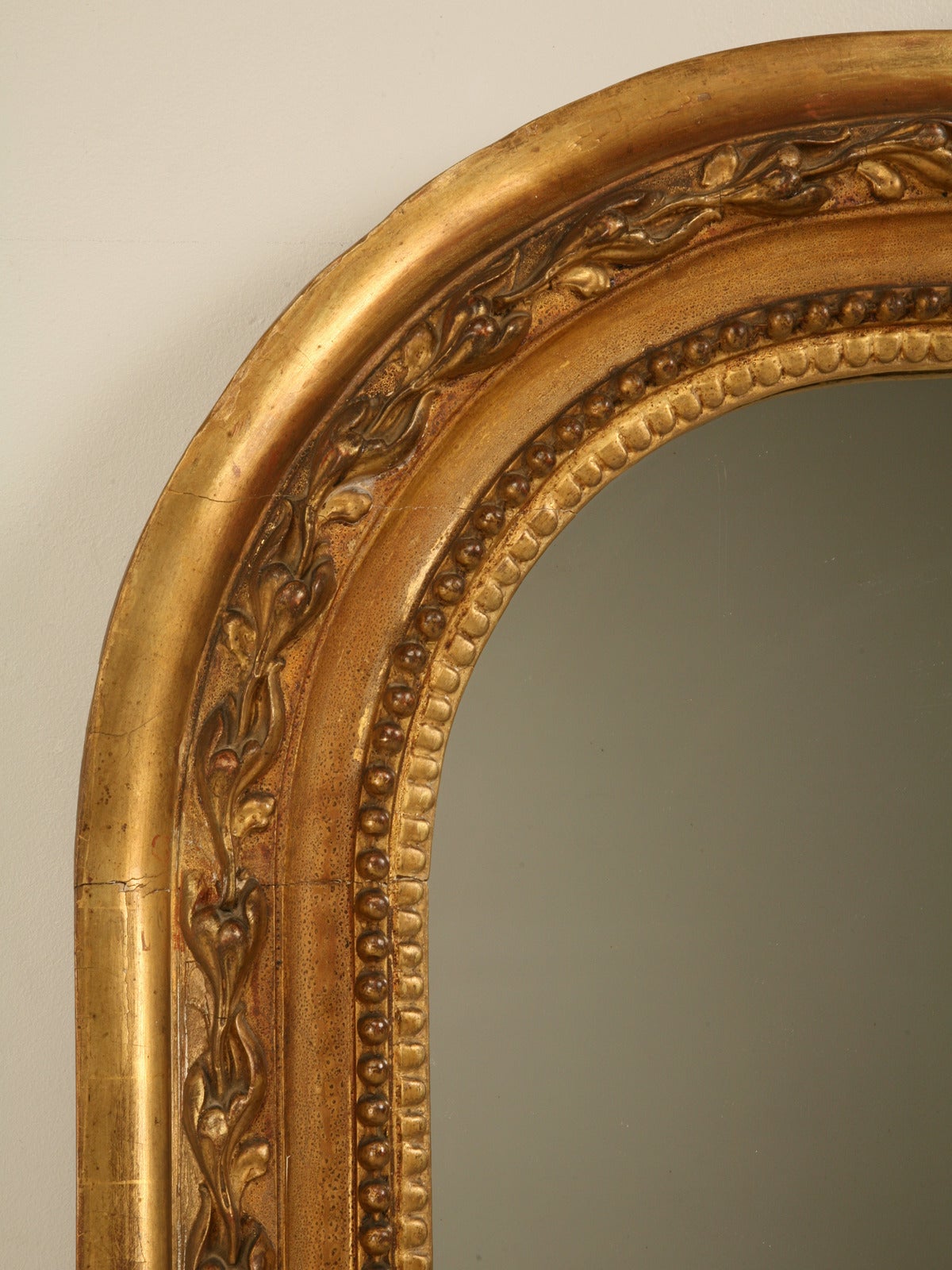 Extremely unusual shape for a French antique mirror and especially so since it still retains its original water gilded finish. Generally the old mirrors get touched up with what we refer in the trade as; 