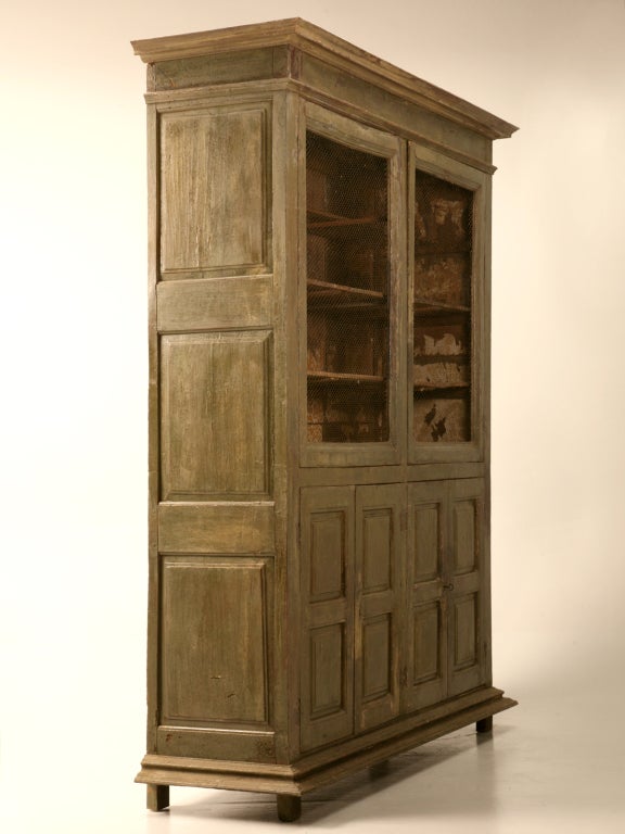 Absolutely incredible early 18th century antique French bookcase or cupboard retaining it's original layered paint, hand-knotted chicken wire and interior wallpaper remnants, too. This amazing cabinet spent 6 weeks in our restoration department