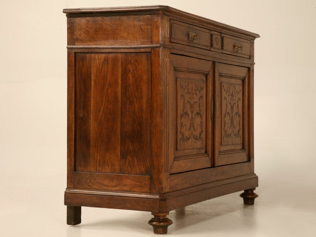 Remarkable antique French Henri II solid oak 2 drawer over 2 door buffet or server. This fine antique offers two smooth functioning drawers with  abundant storage behind the two heavily carved raised panel doors. Fluted details, original hardware