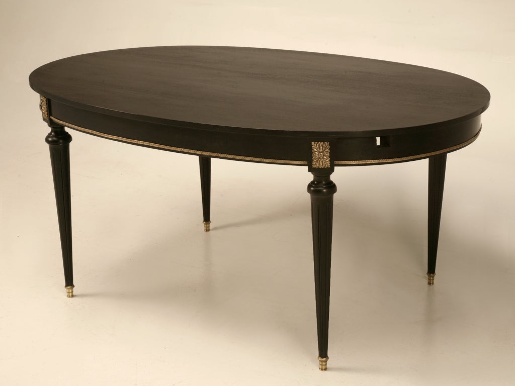 Vintage French Louis XVI style oval to rectangle dining table with a stunning black ebonized finish and stylish metalwork, too. This table boasts a unique option; it is the only table I have ever seen that transforms from an oval shape into that of