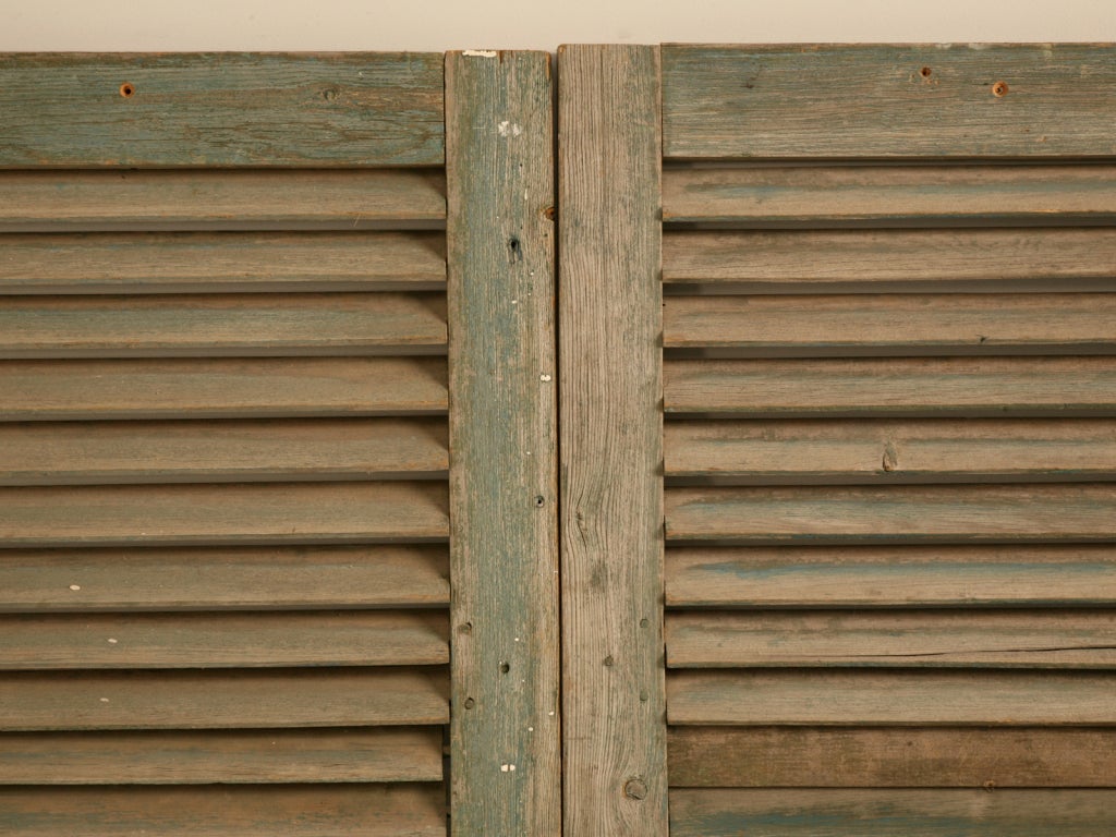 With time-worn, weathered green paint, this incredible pair of antique English shutters are ready to add extra style and pizazz to your home. Whether they are utilized over an existing window to shield Mother Natures bright sunshine, hinged together