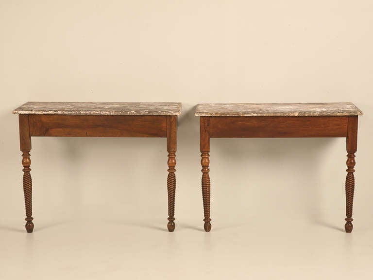 Amazing pair of antique French walnut console tables. These striking tables offer a glimpse into old-world furnishings, with their simple yet, stylish form. Showing a considerable amount of wear on the tops, you may decide to leave them as shown,