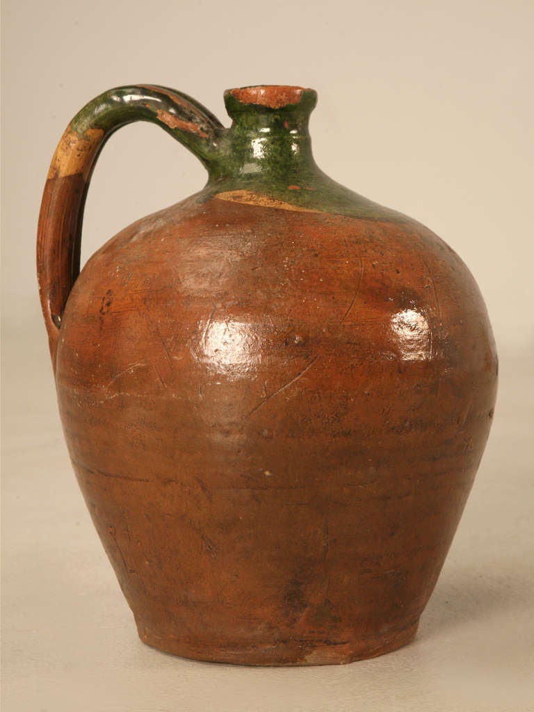 Delightful early antique French handmade earthenware wine jug. This jug has an awesome shape, gorgeous coloring and retains its original handle too. It rarely gets any better than this. Made about mid-nineteenth century, this jug is unparalleled in