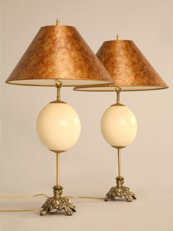 Incredible pair of vintage ostrich egg lamps with ornate brass bases and signed Frederick Cooper designer shades. Perfect so many places, this pair offers natural beauty to any room of the home. The pale creamy color of the eggs with their numerous