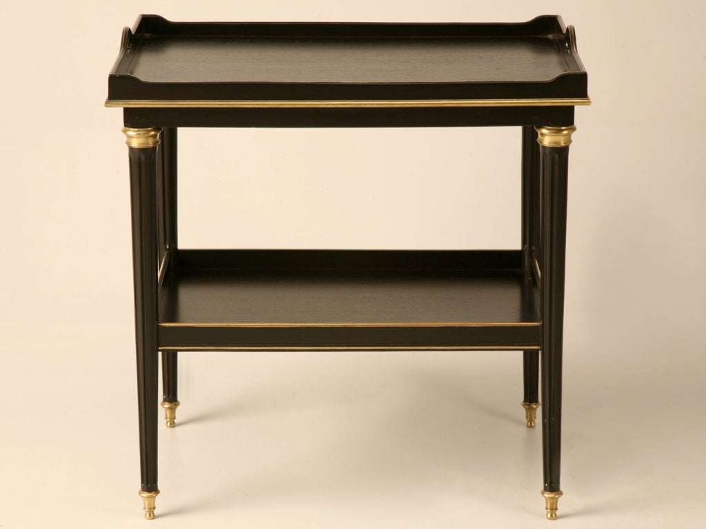 Magnificent vintage French Louis XVI style ebonized mahogany butlers type tea table with polished brass accents and recessed double sliding pull-out shelves as well. This extraordinary table would be awesome at the end of a stylish sofa, next to the