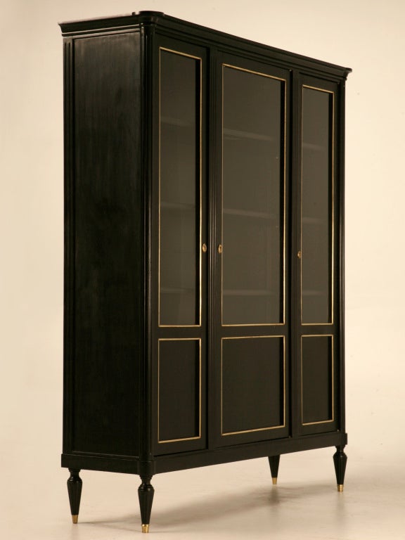 Elegant, sophisticated, and refined are all elements of this gorgeous ebonized Louis XVI cabinet with its three glazed doors and its original polished brasses, too. This style is currently all the rage with designers worldwide, because it is