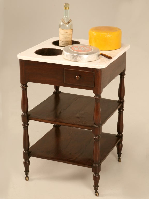 French mahogany rafraichissoir with beautiful hand-turned legs, a hand-dovetailed drawer, and original brass casters. The two original buckets hold and chill wine. The 2 lower shelves hold plates while the naturally cool marble top lets you serve
