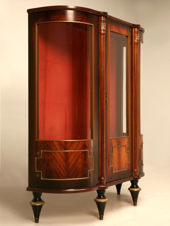 Glamorous petite vintage French Louis XVI style crotch or flamed mahogany china cabinet with curved ends and both Empire and Louis XVI influences. Ornamental brasses add character to this already alluring cabinet. Perfect in a small dining or